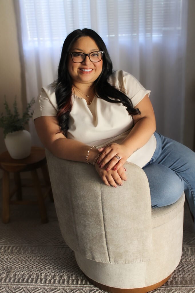 Therapist Rebecca Lopez sitting on a chair, smiling at the camera